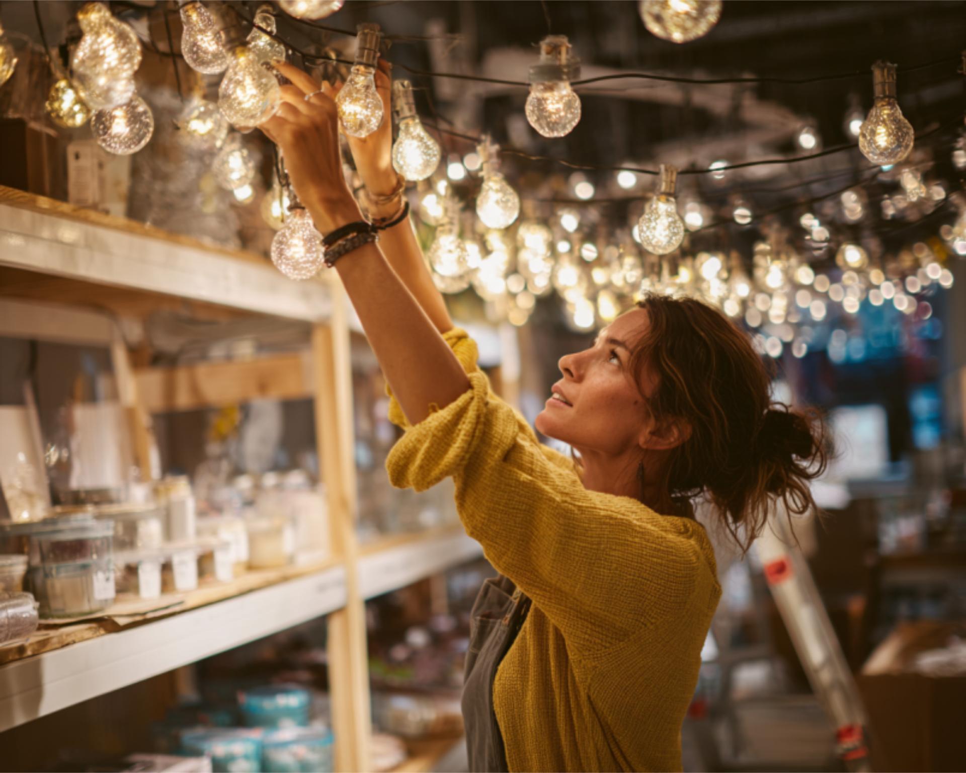 Hands Adjusting String Lights Over Shelves A candi